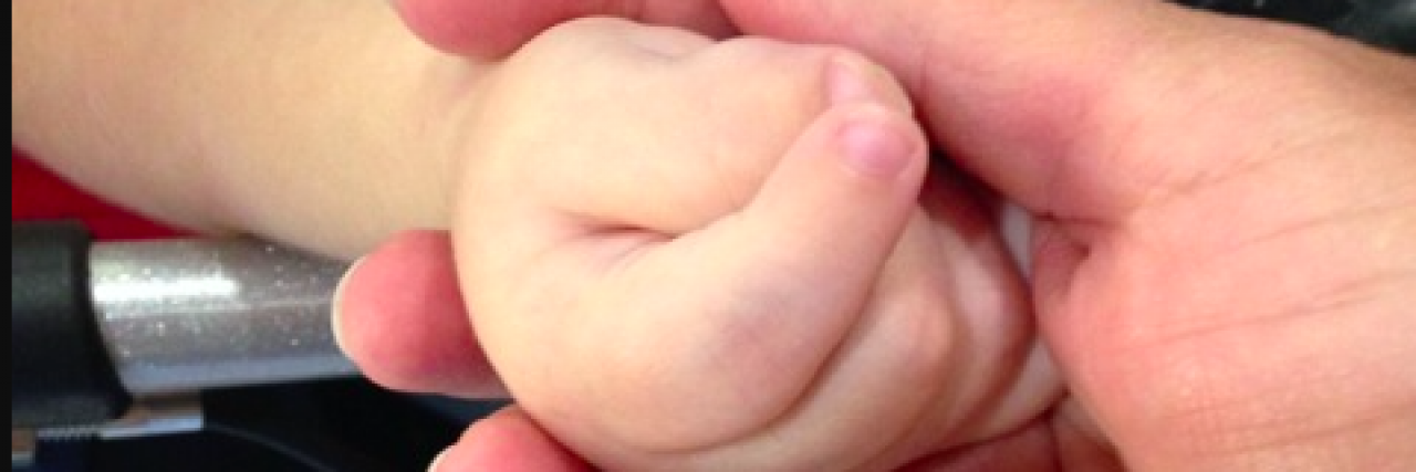 Close up of mother's hands holding young son's