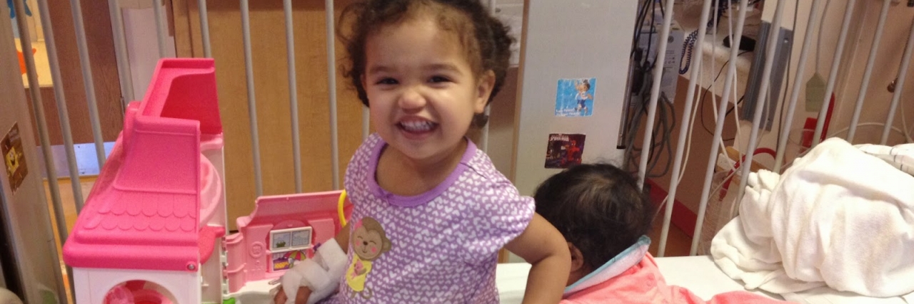 What to Know When Your Child Is Diagnosed With Urea Cycle Disorder young girl playing and smiling in her crib