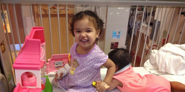 young girl playing and smiling in her crib