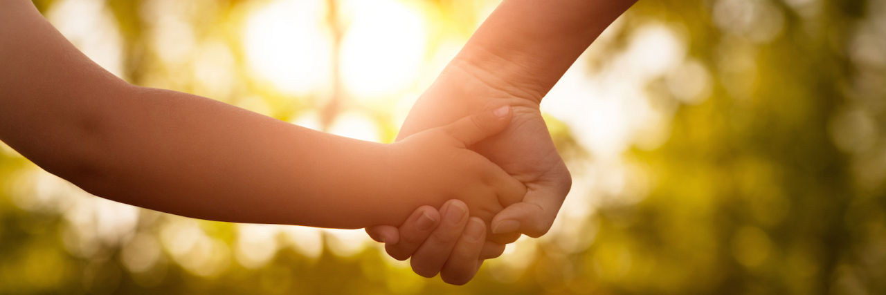 Mother and child holding hands outdoors