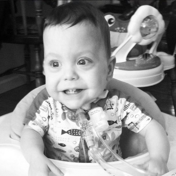 young boy smiling and sitting in a highchair