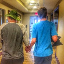 two friends holding hands walking in the hall