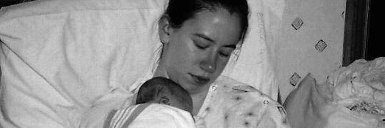 A mom holding her small newborn close to her chest in a hospital bed