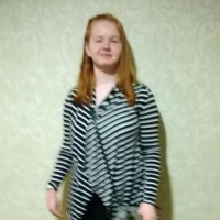 woman in black and white striped shirt standing against green wall