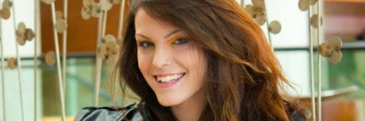 Fibrous Dysplasia: A Letter to My Rare Bone Disease Christina in a white dress and black jacket, sitting on a yellow couch