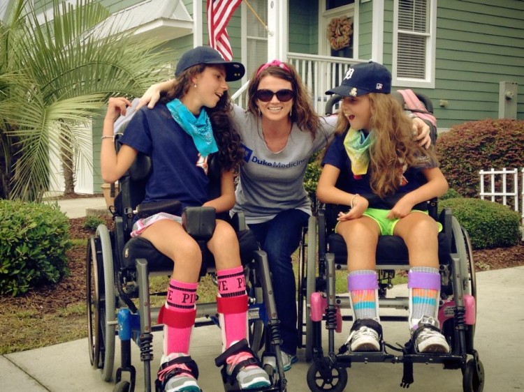 abbey posing in the middle of her two friends in wheelchairs smiling