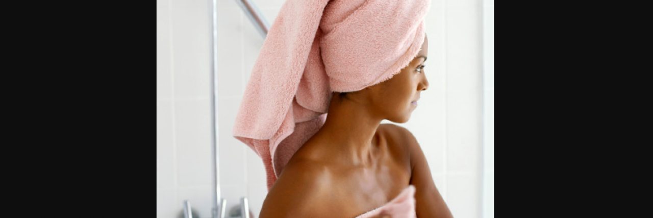 The First Time I Looked at My Mastectomy Scar Black woman with towel wrapped around her in bathroom by shower