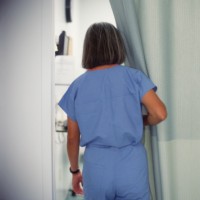 Woman in hospital near hospital curtain