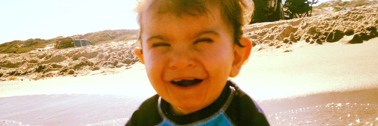 What I Hate Most About My Son's Rare Condition A smiling boy in sitting in the ocean