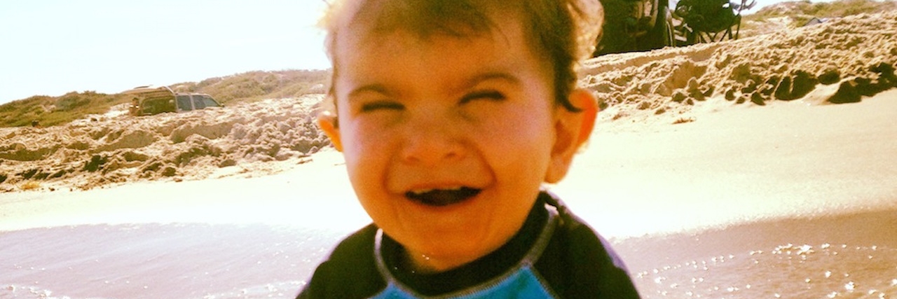 A smiling boy in sitting in the ocean