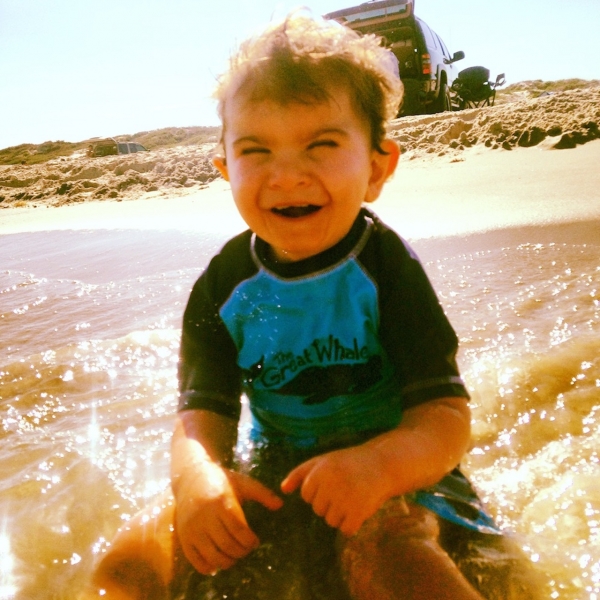A smiling boy in sitting in the ocean