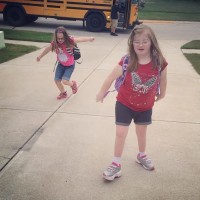 Two girls walking up a driveway as they get off the school bus