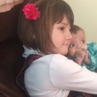 Small girl holds her younger sister