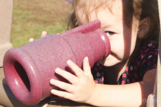 young girl looking through play telescope