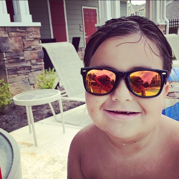 Boy wearing reflective sunglasses next to a pool