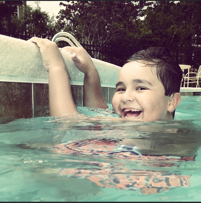 son happily playing in the pool
