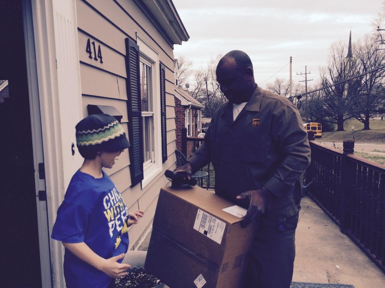 ups delivery man handing package to young boy