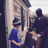ups delivery man hands a package to a young boy
