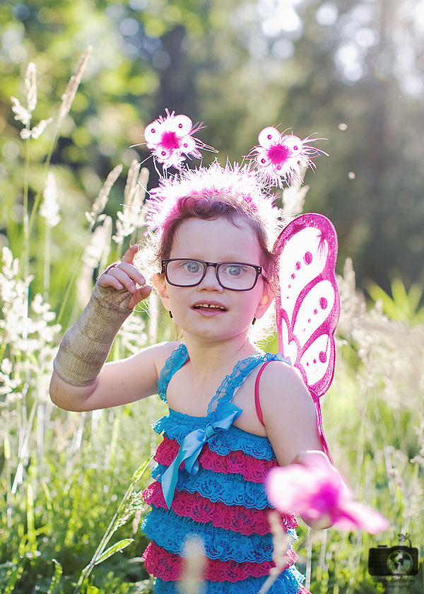 Melanie wearing fairy wings, standing in a grassy field