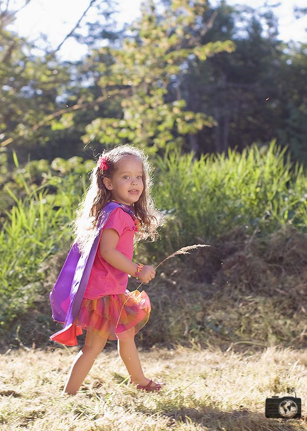 Mila walking in grassy field with a purple cape