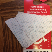 A hand written note on top of a handicapped parking sticker