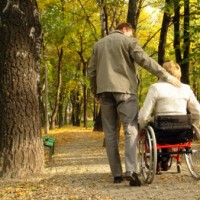 Man and woman in a wheelchair in a park during the fall