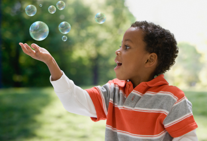 boy catching bubbles outside