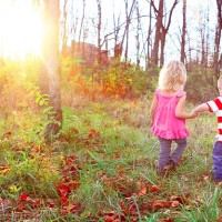 Two kids holding hands as the walk through a forested area