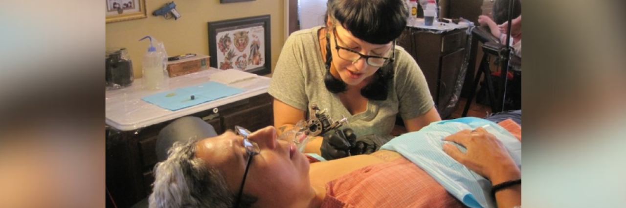Contributor getting tattoo on her chest by tattoo artist