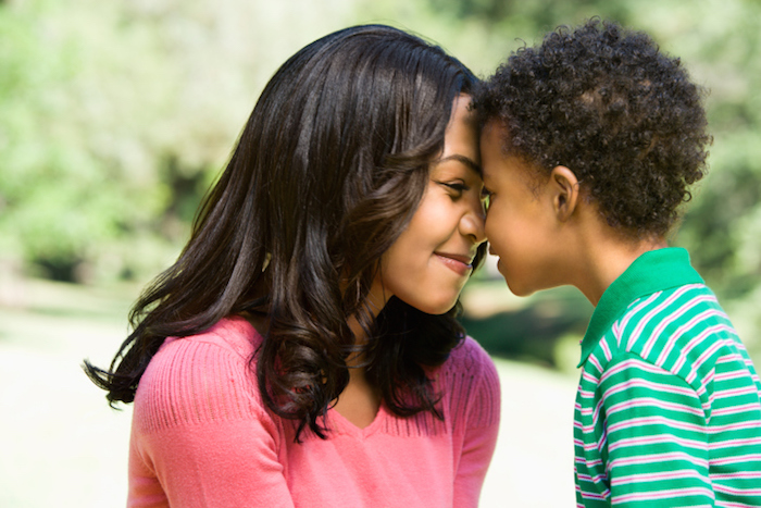 Mother and young son with heads together smiling