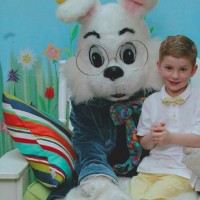 a boy sits on the lap of a person dressed in a bunny costume