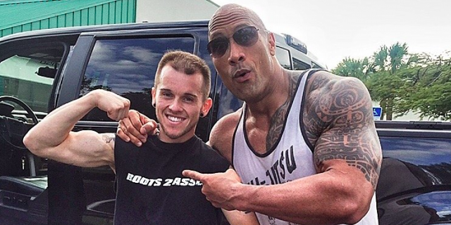 The Rock posing and pointing at fan Nick Miller, who is showing off his own arm muscles