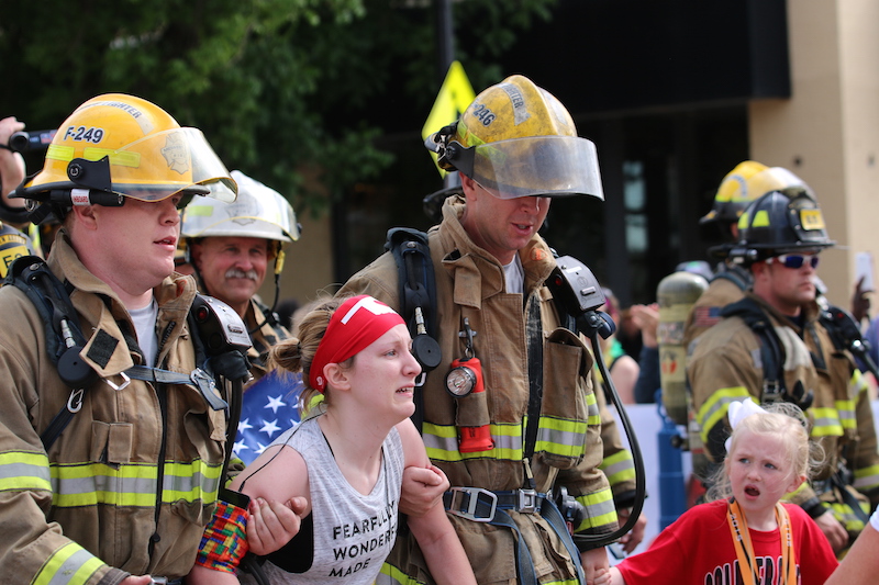 firefighters help kayley cross the finish line