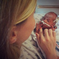 woman touching preemie baby hand