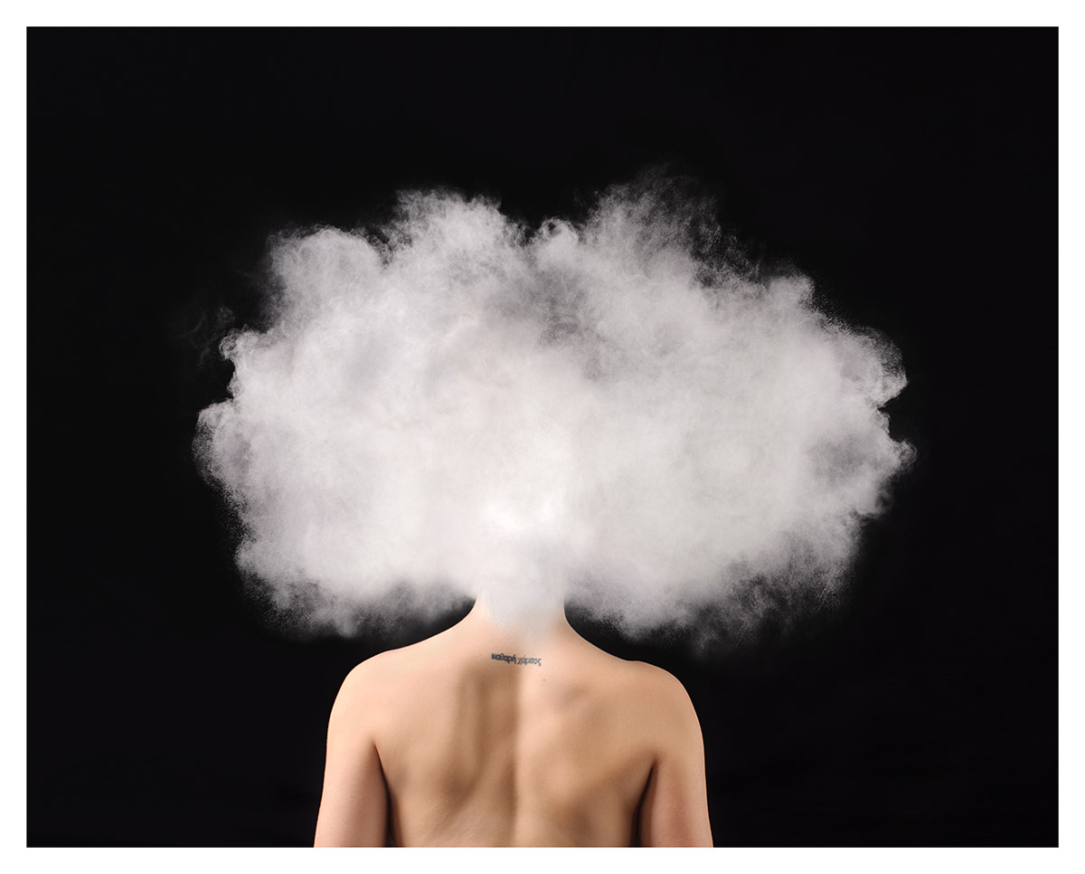 A woman faces backwards -- there's a cloud where her head should be. 