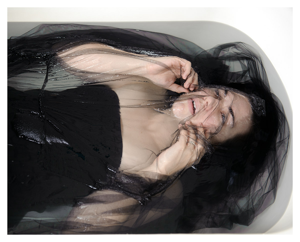 A woman lies in a tub of water. 