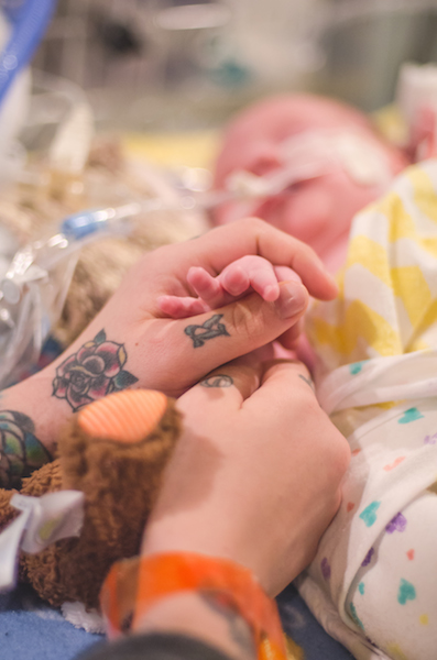 mother's hands holding preemie's hand