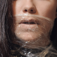 A woman stands wrapped in plastic wrap from her mouth down.