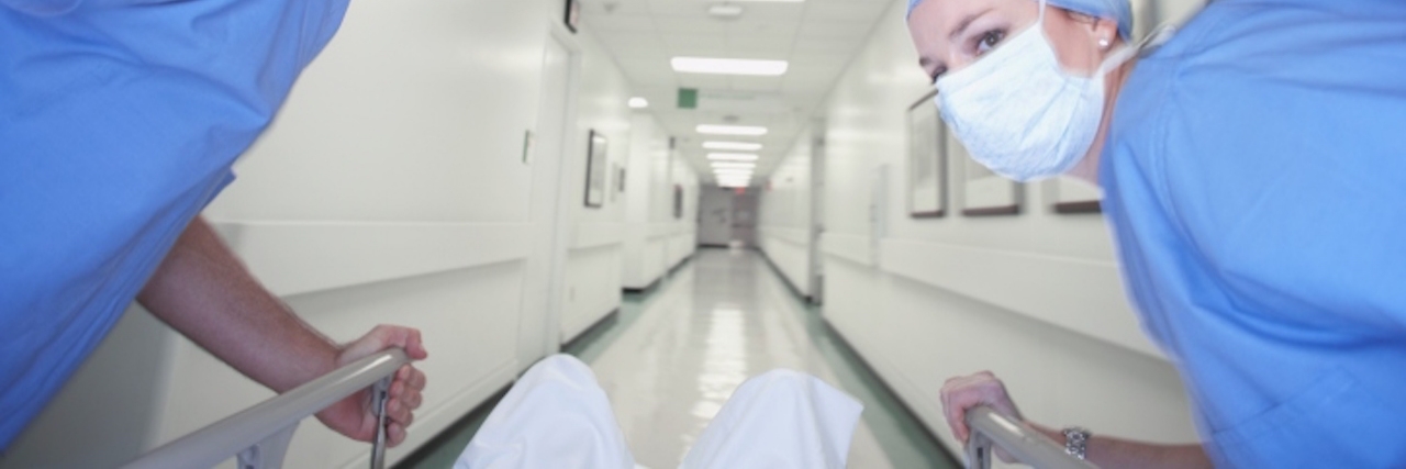 Male and female doctors wheeling gurney down corridor