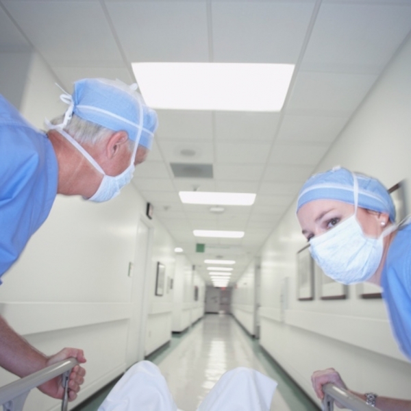 Male and female doctors wheeling gurney down corridor