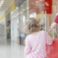 young girl holding mom's hand in shopping mall