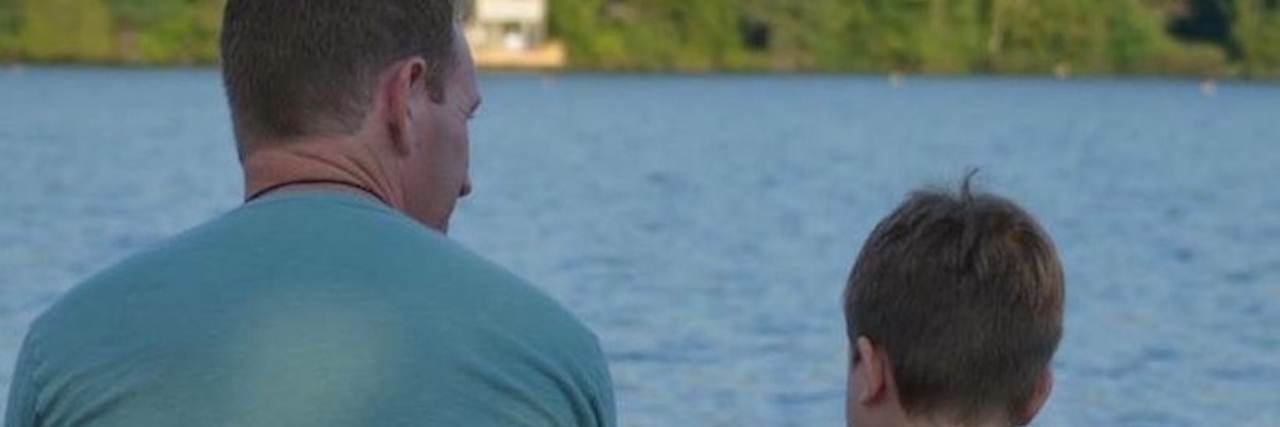What It's Like to Be an Autism Dad dad and son sitting near the lake