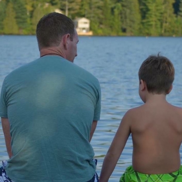 dad and son sitting near the lake
