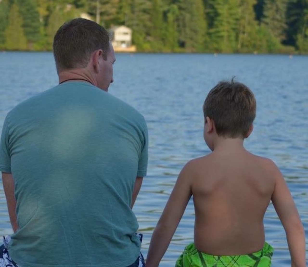 dad and son sitting near the lake