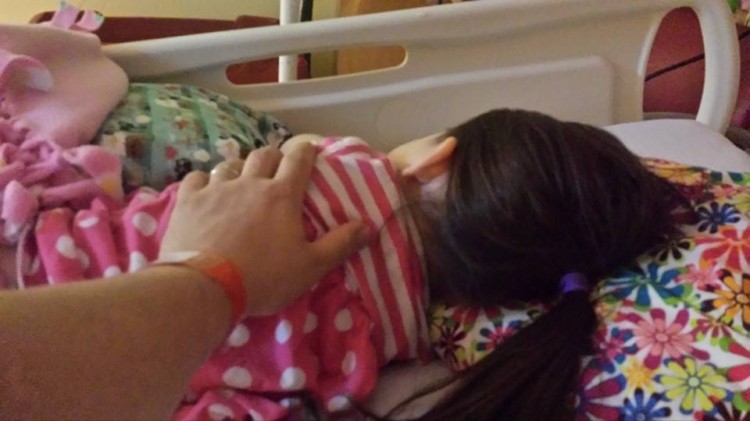 Dad giving support to daughter in hospital bed