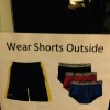 A sign that says "Wear Shorts Outside" and as a picture of a pair of black shorts with a yellow stripe and pairs of black, red and blue underwear