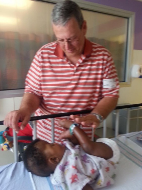 Dad standing next to hospital bed baby is lying on