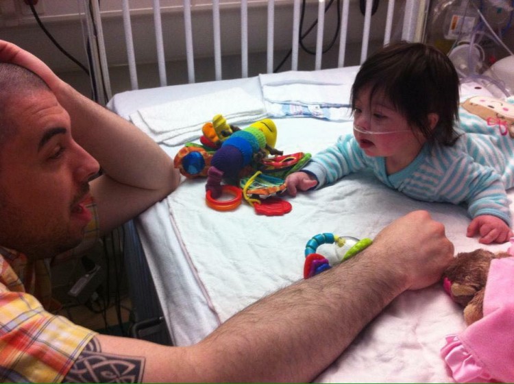 Dad sitting in front of hospital bed with baby and toys