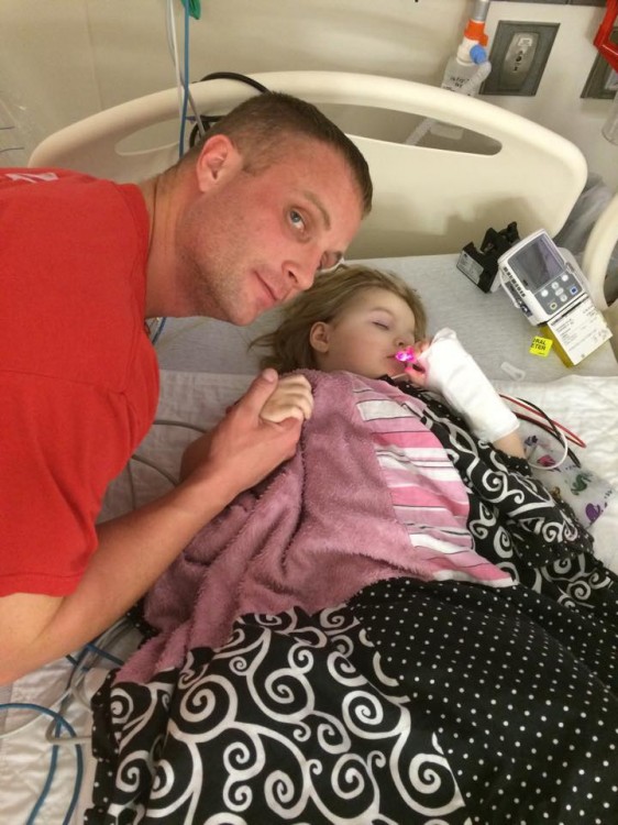 Dad holding daughter's hand while she sleeps in hospital bed