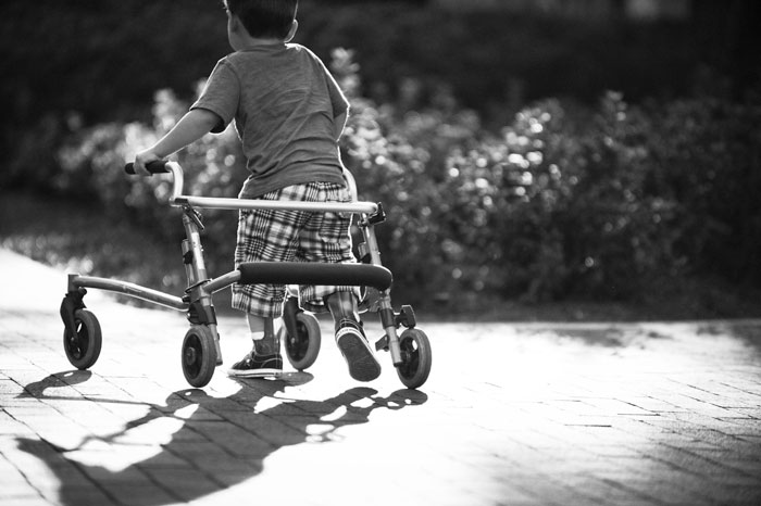 Black and white photo of child walking with walker